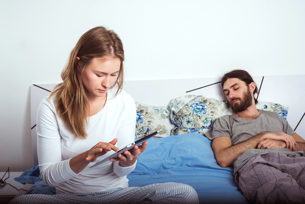 young caucasian couple using tablet in bed - Foto, Bild