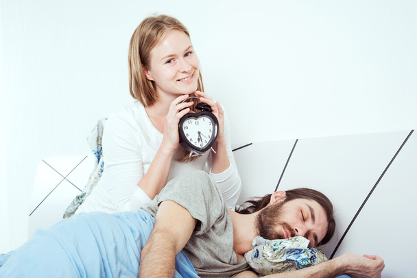 young caucasian couple in bed with alarm clock - Fotó, kép