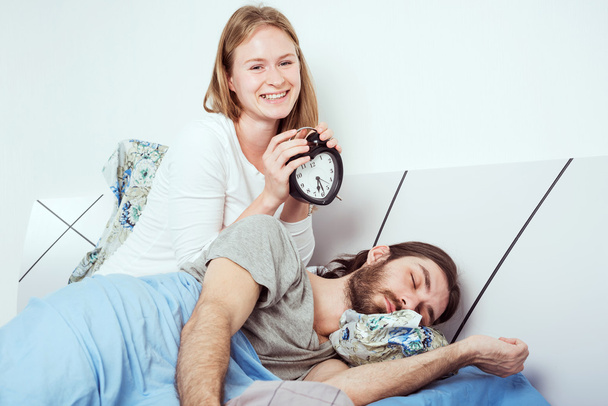 νεαρό ζευγάρι καυκάσιος στο κρεβάτι με το ρολόι συναγερμών - Φωτογραφία, εικόνα