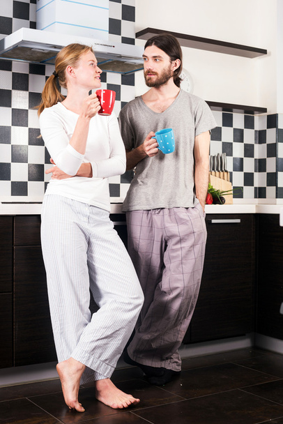young happy smiling caucasian couple on kitchen drinking morning coffee and talking to each other - Φωτογραφία, εικόνα