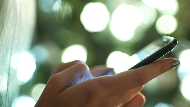 női kéz tart egy modern érintőképernyős telefon és elmosódott kép - Felvétel, videó