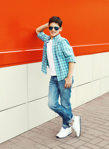 Stylish child boy wearing a sunglasses and shirt in city over re - Фото, изображение