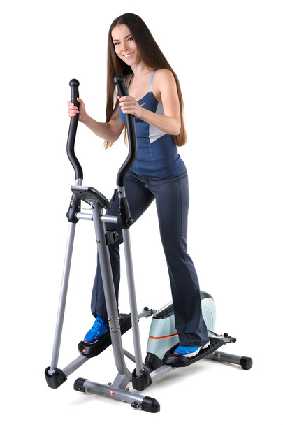 jonge vrouw doen oefeningen op elliptische trainer - Foto, afbeelding