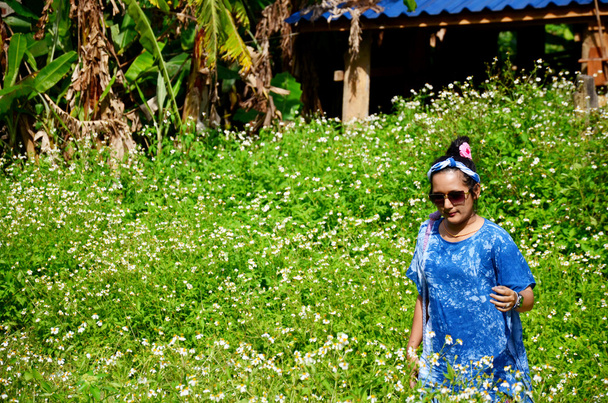 Retrato de mujer tailandesa con campo de flores de aguja español
 - Foto, imagen