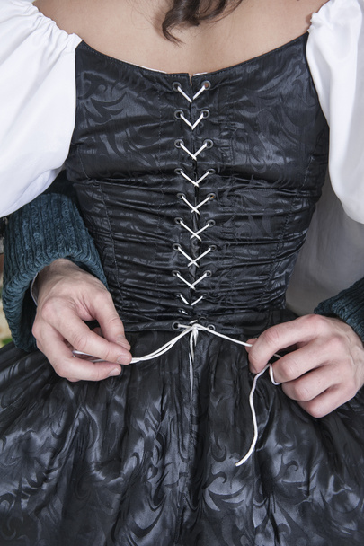 Άνθρωπος τα χέρια αποδέσμευση κορσέ γυναίκας στο μεσαιωνικό φόρεμα - Φωτογραφία, εικόνα