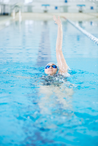 Young girl in goggles swimming back crawl stroke style - Foto, imagen