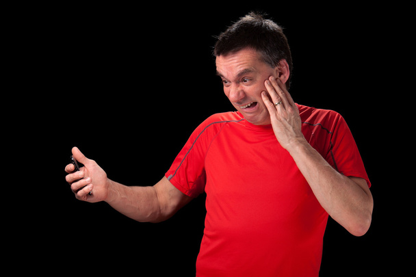Mann mittleren Alters mit schockierter entsetzter Miene beim Anblick des Telefons - Foto, Bild