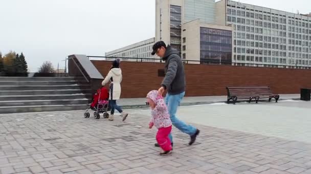 Nuori perhe lapsen kanssa kävelee kadulla
 - Materiaali, video