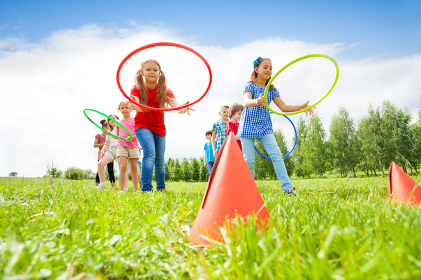 Happy girls and boys throwing colorful hoops - Valokuva, kuva