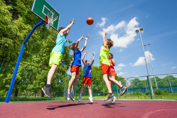 Children jump for flying ball during basketball - Foto, Imagen