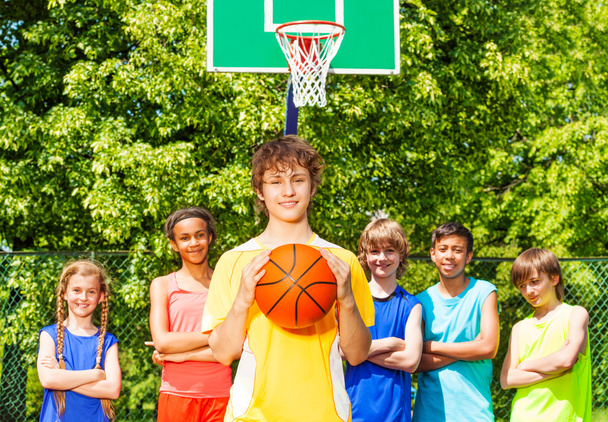 Boy holds ball and his friends standing behind - Φωτογραφία, εικόνα