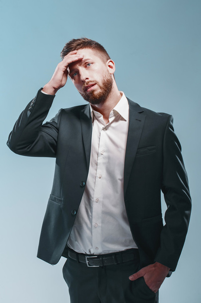 Studio shot of a stylish bearded man in elegant suit, colored tiffany background, isolate thinking, sad, very emotionally - 写真・画像