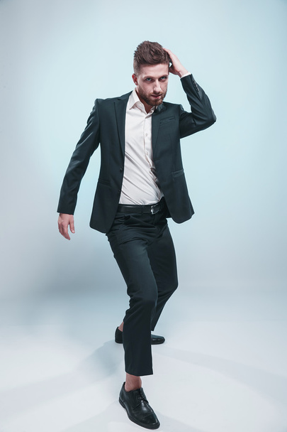 Studio shot of a stylish bearded man in elegant suit, colored tiffany background, isolate - Foto, Imagem