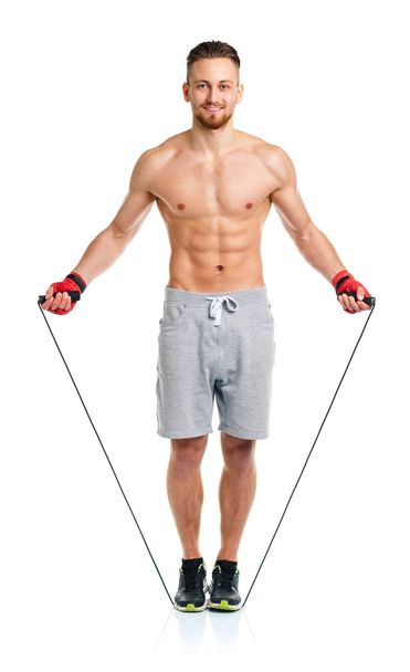 Athletic attractive man jumping on a rope on the white - Photo, image
