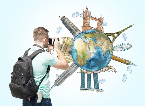 A tourist shoots the globe with sketched famous places. Light blue background. Elements of this image furnished by NASA. - Photo, Image