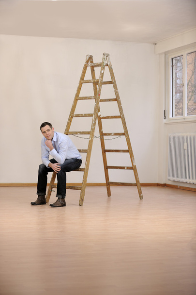 Déménagement dans un nouveau bureau ou une nouvelle maison : un homme assis sur une échelle
 - Photo, image