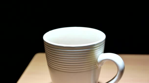 Verter agua caliente en una taza de café sobre un fondo negro
 - Metraje, vídeo
