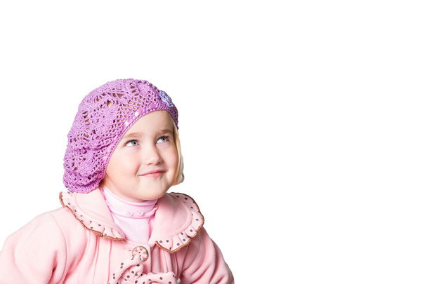 Klein meisje in een roze vacht en baret op witte achtergrond. - Foto, afbeelding