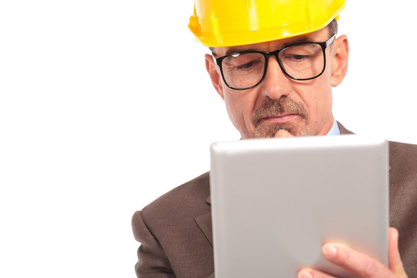 Besorgter Bauingenieur liest auf seinem Tablet - Foto, Bild
