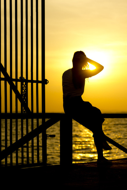 Foto D'archivio Foto D'archivio: Profilo di una donna silhouette guardando il sole sulla spiaggia al tramonto
 - Foto, immagini
