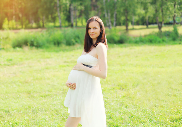 Doğa üzerinde beyaz elbiseli güzel genç hamile kadın - Fotoğraf, Görsel