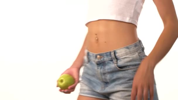 Mujer delgada con manzana en la mano, girando, sobre fondo blanco
 - Imágenes, Vídeo