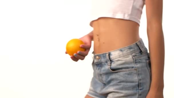 Deportiva mujer con naranja en la mano, girando, sobre fondo blanco
 - Imágenes, Vídeo