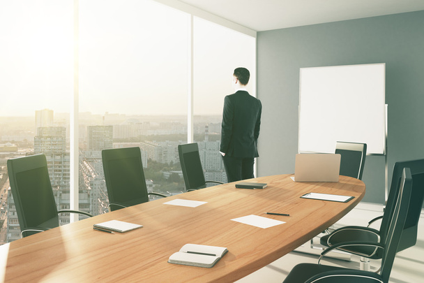Businessman in modern conference room with blank board and city - Photo, Image