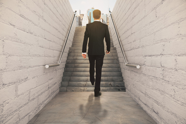 Businessman isclimbing up the stairs between brick walls and con - Photo, Image
