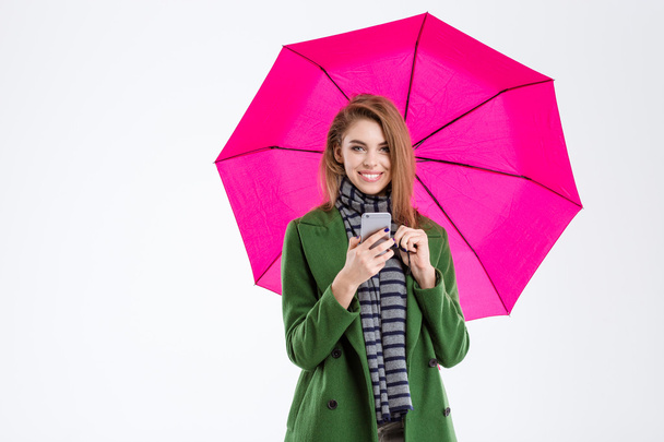 Woman holding smartphone under umbrella - Photo, Image