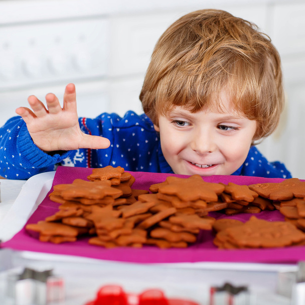 Little kid boy baking Christmas cookies at home - Фото, изображение