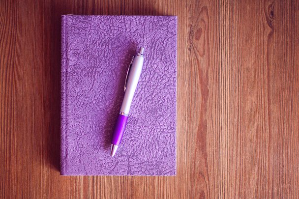 Carnet violet et stylo sur table en bois
 - Photo, image