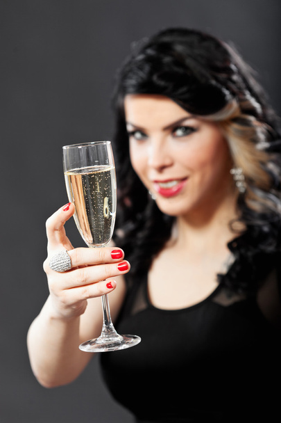 Beautiful young woman celebrating with a glass of champagne - Фото, изображение