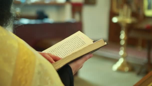 De priester in de kerk verbrijzelt de pagina in de Bijbel - Video