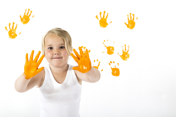 kleines Mädchen bemalt eine Wand mit orangefarbener Farbe - Foto, Bild