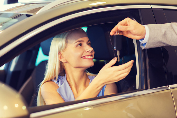 happy woman getting car key in auto show or salon - Φωτογραφία, εικόνα