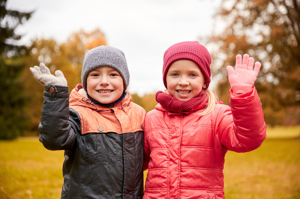 happy girl and boy waving hands in autumn park - Photo, Image