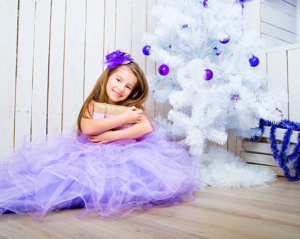 little girl with a gift   near Christmas tree - Foto, afbeelding