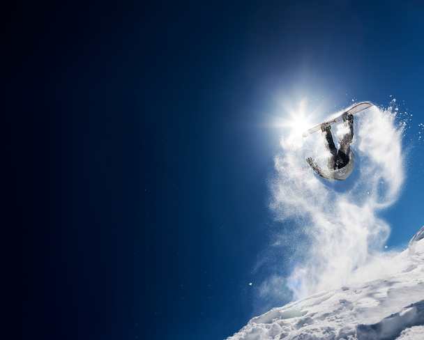 Сноубордист прыгает высоко в ясном голубом небе
 - Фото, изображение