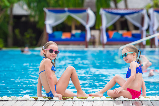 Adorable little girls having fun in outdoor swimming pool on summer vacation - Fotó, kép