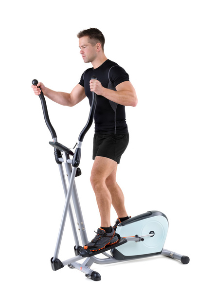 young man doing exercises on elliptical trainer - Valokuva, kuva