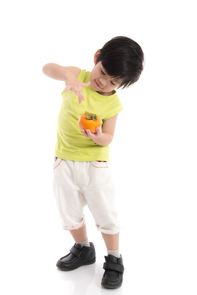 Cute asian boy holding persimmon - 写真・画像