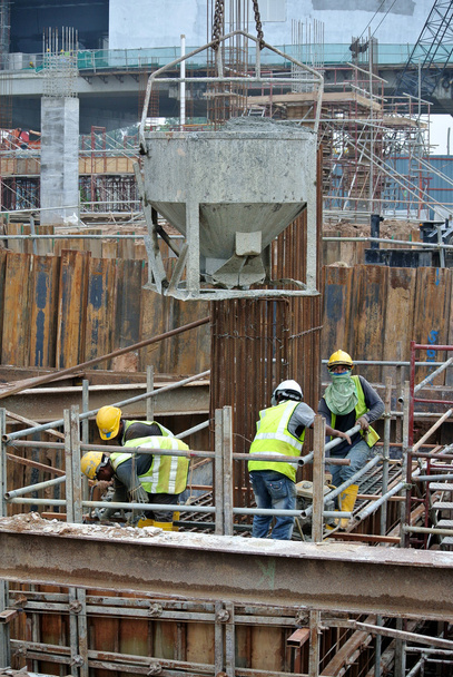 Un grupo de trabajadores de la construcción vertiendo lodo de hormigón en el encofrado de la tapa de la pila
 - Foto, imagen