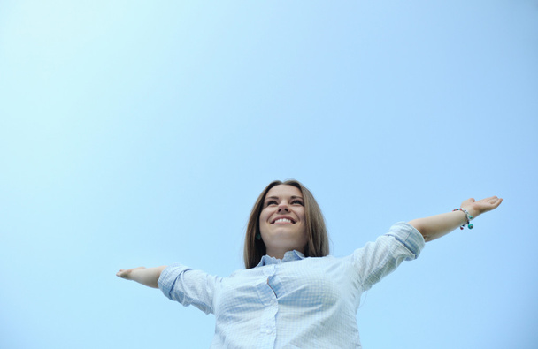 счастливая симпатичная девушка, наслаждающаяся летом на фоне голубого неба
 - Фото, изображение