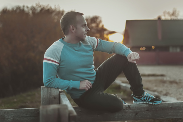 Attractive man sitting on beach in the evening  after sport. - Foto, Bild