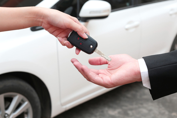 Γυναικείο χέρι δίνει ένα κλειδί για τον αγοραστή ή ενοικίασης αυτοκινήτων. - Φωτογραφία, εικόνα