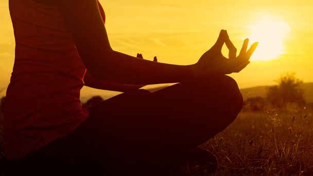 Jovem atlética praticando ioga em um prado ao pôr do sol, silhueta
 - Foto, Imagem