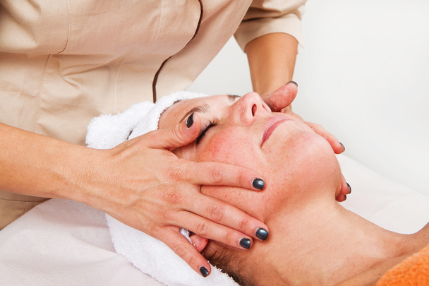 Mulher bonita recebendo massagem facial com olhos fechados
 - Foto, Imagem