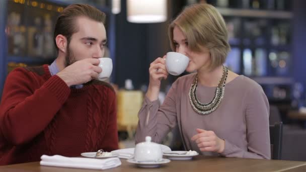 Portrait of young beautiful couple in love having coffee in beautiful cafe - Felvétel, videó
