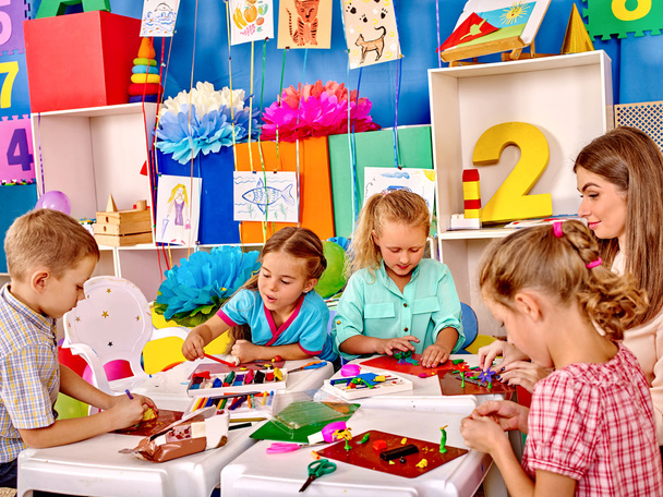 Kids holding colored paper and glue on table in kindergarten . - Photo, Image